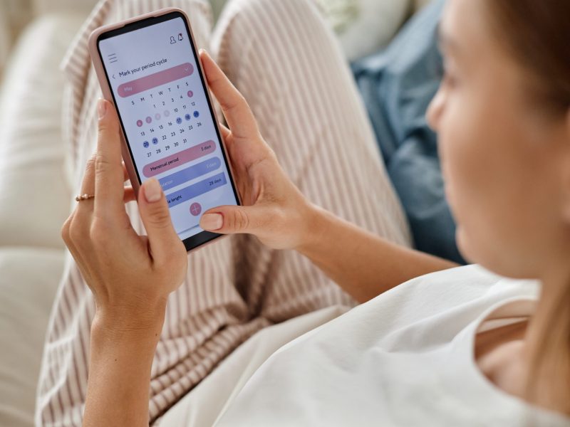 Caucasian,Young,Adult,Woman,Holding,Smartphone,While,Checking,Menstrual,Cycle